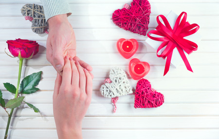 St. Valentine's Day, Love concept. Young couple taking hands, over holiday decorated wooden background. Top view, tabletopの写真素材