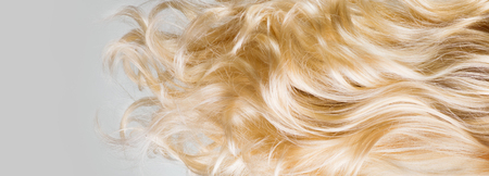 Hair. Beautiful healthy long curly blond hair closeup texture. Dyed wavy blonde hair background. Coloring concept. Haircareの写真素材