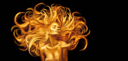 Golden beauty woman. Sexy model girl with golden makeup and long hair pointing hand over black.の写真素材
