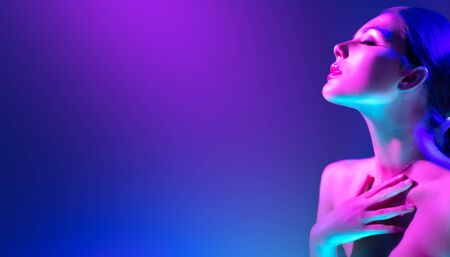 Fashion model woman in colorful bright neon lights posing in studio. Portrait of beautiful girl in UV. Art design colorful makeupの写真素材