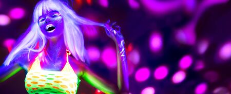 Neon Woman dancing. Fashion model woman in neon light, portrait of beautiful model with fluorescent make-up, Art design of female disco dancer posing in UV, colorful make up. On bright backgroundの写真素材