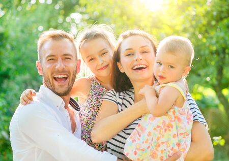 Happy joyful family. Young parents and they little kids having fun outdoors in autumn parkの写真素材