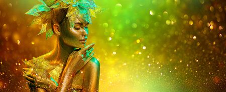 Golden Fashion model woman with bright golden sparkles on skin posing, fantasy flower, portrait of beautiful girl glowing makeup. Art design gold sequins make up. Glitter glowing skin, jewellery, neonの写真素材
