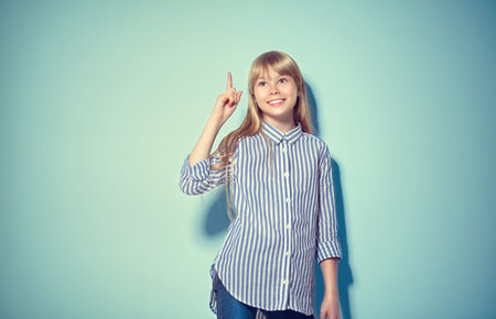 Beauty funny blonde teenage girl has an idea, pointing finger, showing empty copy space for text,...