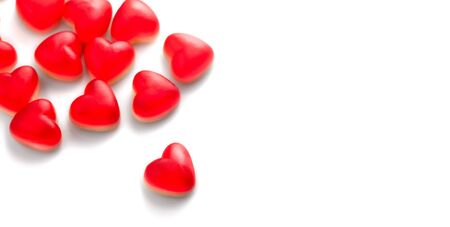 Heart shaped jelly candy, love background. Red jelly sweets candies on white backdrop. St. Valentines, marriage hearts border background. Closeupの写真素材