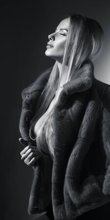 Beauty Fashion Model Girl in Mink Fur Coat black and white portrait. Beautiful Woman in Luxury Brown Fur Jacket posing in studio. Expensive wear, Winter Fashion, elegant styleの写真素材
