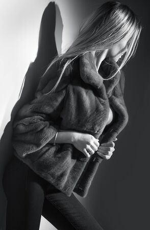 Beauty Fashion Model Girl in Mink Fur Coat black and white portrait. Beautiful Woman in Luxury Brown Fur Jacket posing in studio. Expensive wear, Winter Fashion, elegant styleの写真素材