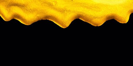 Golden dripping liquid paint texture, isolated on black background. Flowing abstract Gold metallic paint drops close-up. Leaking Lipgloss, blots of nail polish closeup. Border art designの写真素材