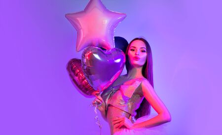 Valentine Beauty girl air balloons laughing in neon lights, on ultra violet background. Beautiful Happy Young woman, holiday party. Joyful model posing, having fun, celebrating  Valentine's Dayの写真素材