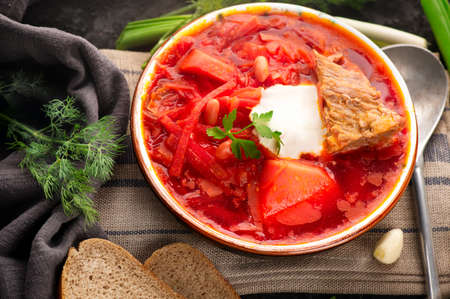 Traditional Ukrainian Russian borscht with white beans on the bowl. Plate of red beet root soup borsch on black rustick table. Beetroot soup Top view. Traditional Ukraine food cuisine.の写真素材