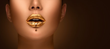 Golden lipstick closeup. Liquid metal dripping from gold lips. Beautiful makeup. Sexy lips, bright liquid paint on beautiful model girl's mouth, close-up. Lipstick.の写真素材