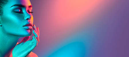 Model woman in colorful bright sparkles and neon lights posing in studioの写真素材