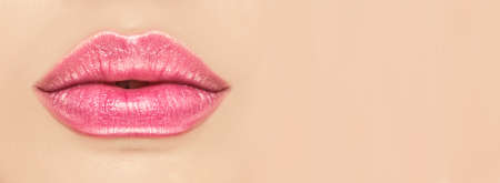 Beautiful young woman's lips closeup, on beige background. Plastic surgery, fillers, injection. Part of the model girl face, youth concept. Perfect healthy skin. Natural make-up. Health careの写真素材
