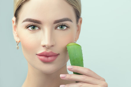 Skin care. Beauty Woman with perfect skin holding fresh leaf of Aloe Vera. Portrait of Beautiful Blonde Spa Girl with perfect healthy skin. Skincare, moisturizing. Proposing a skin care productの写真素材