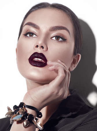 Beauty Fashion model girl with dark lips portrait, wearing stylish sexy woman portrait with perfect makeup, trendy accessories and fashion wear. Beauty trends. Perfect skin. White backgroundの写真素材