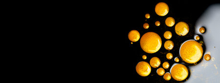 Gold paint drops sample stroke isolated on black background. Flowing abstract Gold metallic paint smudges close-up. Smears of glittering make-up Lipgloss, blot of nail polish closeup, macro textureの写真素材