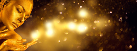 Gold Woman. Christmas magic gift. Beauty fashion model girl with Golden make-up, hair and jewellery on gold magic in a hand. Holding Gold miracle in hand. Metallic glance Fashion art portrait, glamourの写真素材