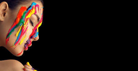 Fashion Model Girl colorful face paint. Beauty art portrait of beautiful woman with flowing liquid paint, abstract makeup. Vivid paint make-up, bright colors Multicolor creative art, isolated on blackの写真素材