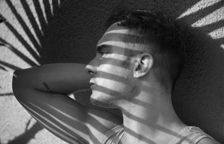 Young man fashion art portrait. Handsome male close up. Black and white portrait of sexy muscular guy posing outside, profileの写真素材