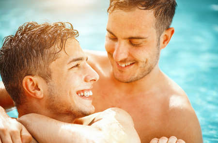 Gay couple relaxing in swimming pool. LGBT. Two young men enjoying nature outdoors, kissing and hugging. Young men romantic family in love. Happiness conceptの写真素材