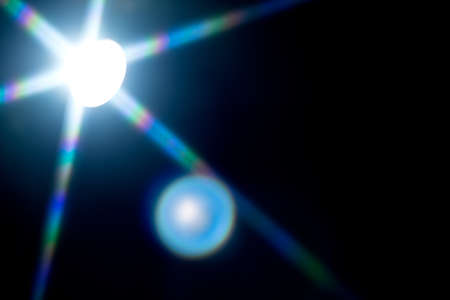 Light Flare over black background. Reflection. Light Ray close up. Studio lights backdrop, lighting for screen mode using. Lens flares. Rays of studio lights macro shotの写真素材