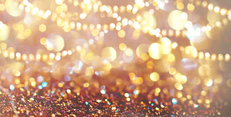 Abstract gold bokeh background. Golden holiday glowing backdrop. Defocused Background With Blinking Stars, tinsel and garland. Blurred Bokeh art design. Abstract shiny lights design.の写真素材