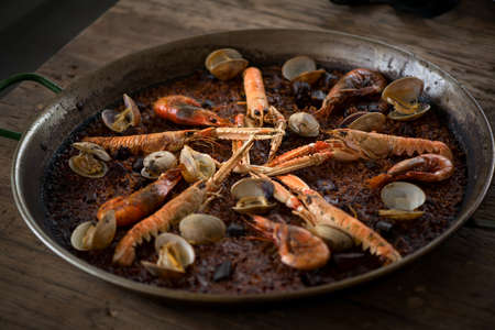 Paella traditional Spanish food, seafood paella in the fry pan with mussels, king prawns, langoustine and squids. Cooking paella, closeup.の写真素材