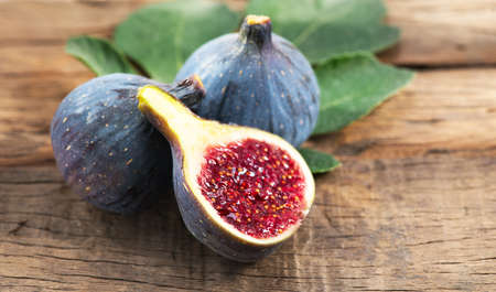 Ripe fig fruits with leaf close-up. Beautiful sweet fresh organic figs on a wooden table. label design. Healthy vegan food.の写真素材