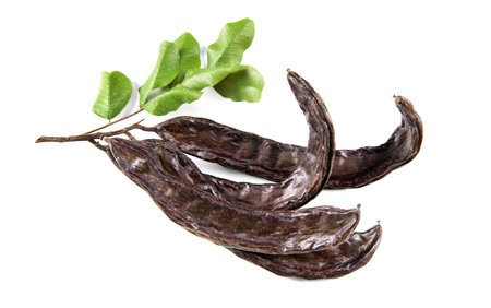 carob. Healthy organic sweet carob pods with seeds and leaves isolated on white. Healthy eating, food background. organic vegan foodの写真素材