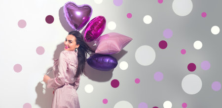 Valentine Beauty girl with colorful heart air balloons laughing, isolated on white background. Beautiful happy young woman. Holiday birthday party, having fun, celebratingの写真素材