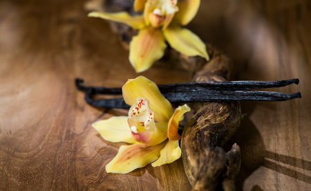 Vanilla flowers and pods close up. Vanilla beans over wooden background, macro shot. Aromatic condiments closeup, flavourの写真素材
