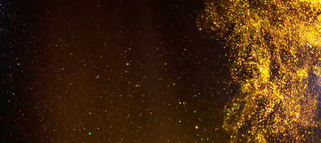 Golden sparks, Christmas and New Year glittering stars swirl on black bokeh background, backdrop with sparkling gold, holiday garland, magic glowing dust, lights. Gold Abstract Gliの写真素材
