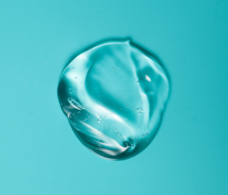 Transparent gel drop. Liquid cream gel cosmetic smudge texture on blue background. Cosmetics serum gel, hyaluronic acid cream background, facial treatmentの写真素材