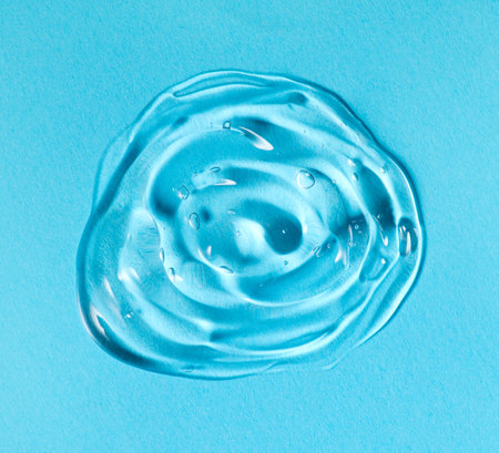 Transparent gel drop. Liquid cream gel cosmetic smudge texture on blue background. Cosmetics serum gel, hyaluronic acid cream background, facial treatment.の写真素材