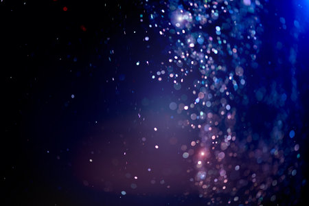 Abstract Glitter Blinking sparks background, Christmas and New Year floating glittering stars on black, blue bokeh backdrop with sparkling holiday garland, magic dust, lights.の写真素材
