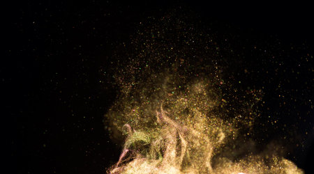 Golden sparks, gold powder, dust, magic Christmas and New Year glittering stars swirl on black background, backdrop with flying sparkling gold, holiday magic glowing lights. Abstraの写真素材