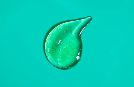 Green gel smear, drop. Liquid cream gel cosmetic smudge texture on green, cyan background. Cosmetics serum gel, hyaluronic acid cream background, aloe vera facial treatment, fluid.の写真素材