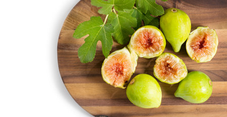 Fig fruits. Ripe sweet yellow and green figs fruit with leaves on wooden table close up, isolated on white background. Top viewの写真素材