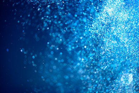 Abstract blue background with floating particles, glowing backdrop. Glitter Blinking sparks background, Christmas and New Year floating glittering stars on blue, bokeh backdrop witの写真素材