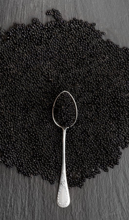 Black Caviar in silver spoon, top view of sturgeon black caviar close-up. Delicatessen backdrop. Texture of expensive luxury caviar background. Vertical image.の写真素材