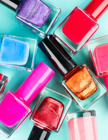 Nail polish colorful bottles. Manicure concept. Top view. Nailpolish colourful bottles over blue background, border backdrop. Nail polish red, pink, violet colors shellac UV gel, vの写真素材