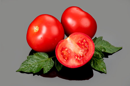 Tomato. Ripe natural tomatoes close-up. Organic tomato with leaves on gray background. Macro shot. Half of tomato close-up. Garden, Gardening concept. Ketchup, pasta, sauce ingrediの写真素材