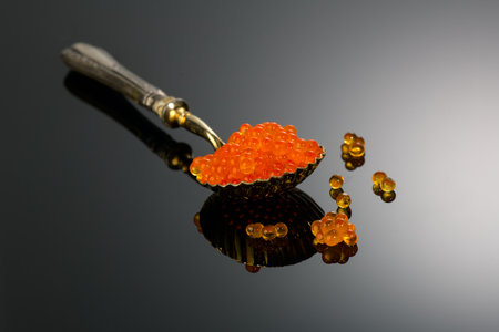 Red Caviar in a spoon over gray background. Close-up of salmon fish roe caviar. Delicatessen. Texture of trout caviar. Seafood backdrop.の写真素材