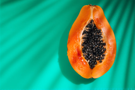 Papaya fruit on tropical green background with shadows of palm tree. Halved fresh organic Papaya exotic fruit close up. Top viewの写真素材
