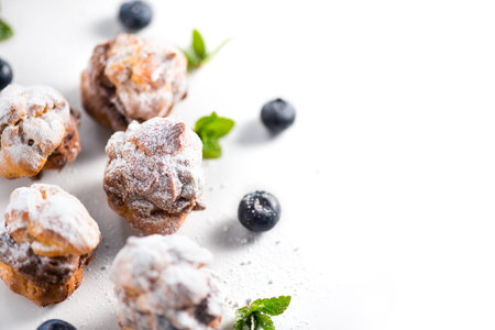 Profiterole or cream puff with filling,  powdered sugar topping with berries, isolated on white...