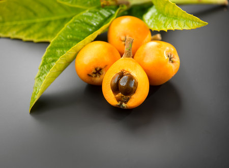 Loquat fruit or Japanese medlars, Nispero, Eriobotrya japonica with leaves fresh ripe bio vegetarian food, medlar berries. Close up. On black background.の写真素材