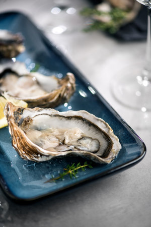 Oysters on plate, open french fresh oyster with lemon, served table in restaurant, dinner with...
