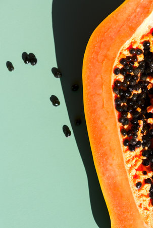 Papaya fruit over green background, half of fresh exotic fruits with seeds. Halved fresh organic Papaya exotic fruit art design, close up. Top view, flat lay, vertical imageの写真素材