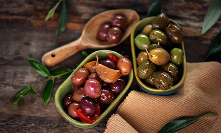 Olives, homemade marinated colorful olives with herbs and spices on rustic table, close up. Healthy Mediterranean vegan food. Vertical image, top view, flat layの写真素材