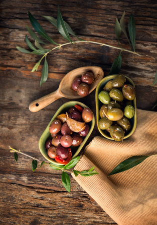 Olives, homemade marinated colorful olives with herbs and spices on rustic table, close up. Healthy Mediterranean vegan food. Vertical image, top view, flat layの写真素材